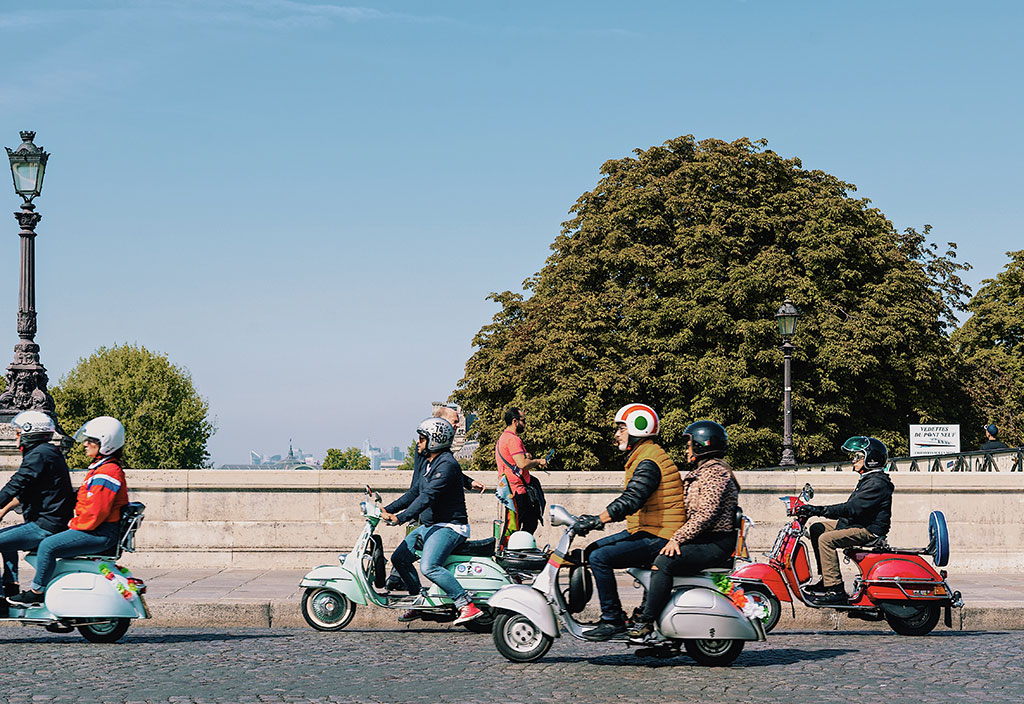 People riding scooters across a bridge in Paris